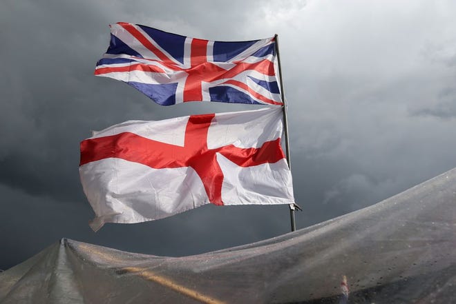 The flag of the United Kingdom of Great Britain and Northern Ireland, top, and the flag of England fly Saturday above a souvenir stand on Westminster Bridge after Friday’s EU referendum result.