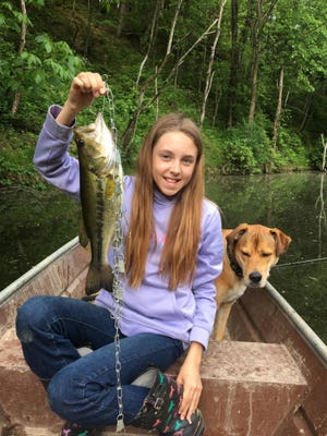 Bailey Wilson, 12, of Dover, shows off her catch at a farm pond at her house. Her dog JoJo also is pictured.