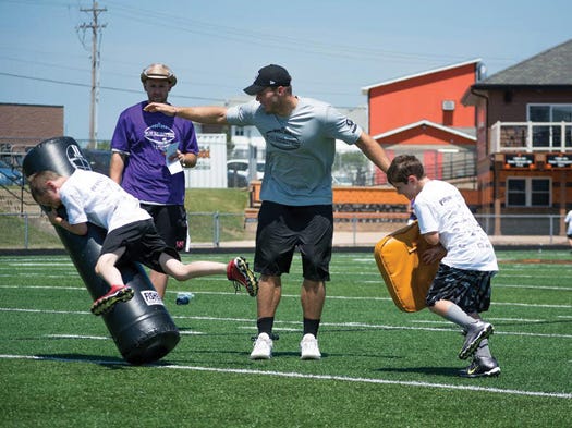 Washington native Colton Underwood works with young campers on proper blocking and tackling techniques during Saturday's football camp at Washington Community High School.