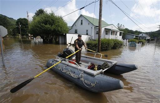 Lt. Dennis Feazell, of the West Virginia Department of Natural Resources, rows his boat as he and a co-worker search flooded homes in Rainelle, W. Va., Saturday.