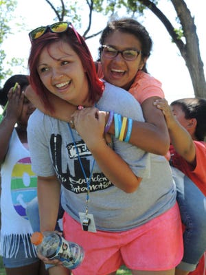 No Boundaries International of Amarillo's Kaytlin Wyatt, 19, left, gives a piggy-back ride to Mary Ann Lopez, 13, at Forest Hill Park. While the children Wyatt works with are not trafficked, the organization sees its outreach as an opportunity to create relationships with members of the community.