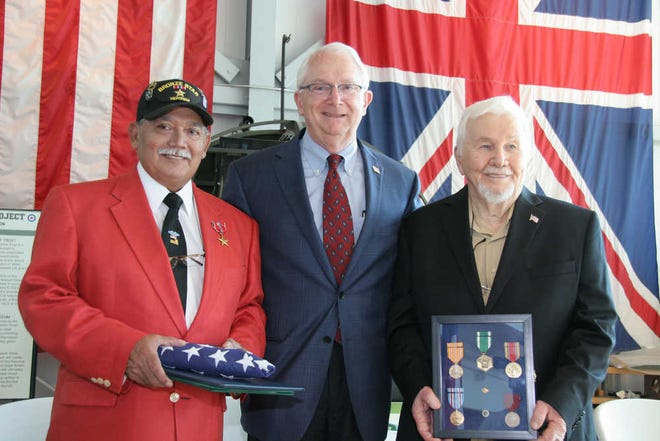 Veterans Jessie Rendon, left, and Andy Winnegar, right, hold a flag and medals as they are recognized by U.S. Rep. Randy Neugebauer.