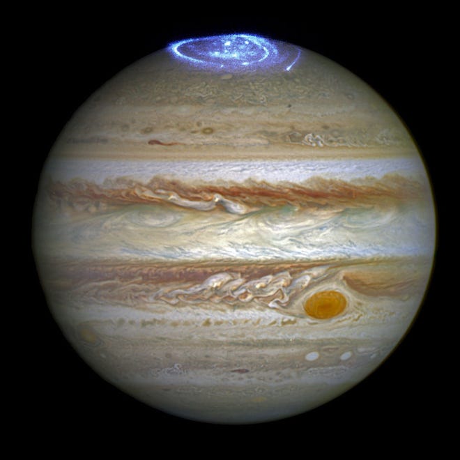 This composite image provided by NASA on Thursday, June 30, 2016 illustrates auroras on the planet Jupiter. This view was produced by NASA using a photograph made by the Hubble Space Telescope in spring 2014, and ultraviolet observations of the auroras in 2016. Earth’s polar lights are triggered by solar storms, which occur when a cloud of gas from the sun encounters the planet’s magnetic field. Jupiter’s powerful auroras are sparked by the planet’s own rotation. (NASA/ESA/Hubble via AP)