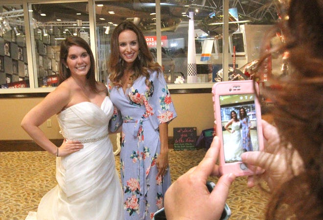 Lauren Durham, left, poises with Samantha Busch, wife of NASCAR driver Kyle Busch on Thursday. The soon-to-be brides take part in Operation Wedding Gown which gifts wedding gowns to brides of military personnel and first responders.  News-Journal/David Tucker