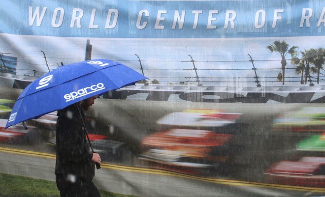 The only fast Sprint Cup cars at Daytona International Speedway Thursday were on a mural in the FanZone, where a fan bides his time during a rain delay. News-Journal/JIM TILLER