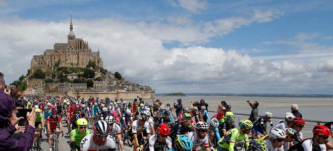 Cyclists start the Tour de France at the Mont-Saint-Michel, rear, on Saturday. The first stage ended at Utah Beach, France.