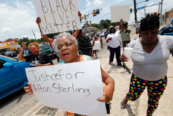 People march outside the Triple S convenience store in Baton Rouge, La., Wednesday, July 6, 2016. Alton Sterling was shot and killed outside the store where he was selling CDs Tuesday by Baton Rouge police. The U.S. Justice Department opened a civil rights investigation Wednesday into the videotaped police killing of Sterling. (AP Photo/Gerald Herbert)