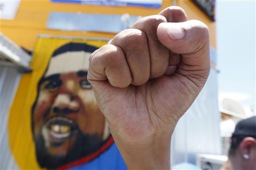 Annie Lanns holds up her fist in front of a mural of Alton Sterling while attorneys, not pictured, speak in front of the Triple S Food Mart in Baton Rouge, La., Thursday, July 7, 2016. Sterling, 37, was shot and killed outside the convenience store by Baton Rouge police, where he was selling CDs. (AP Photo/Gerald Herbert)