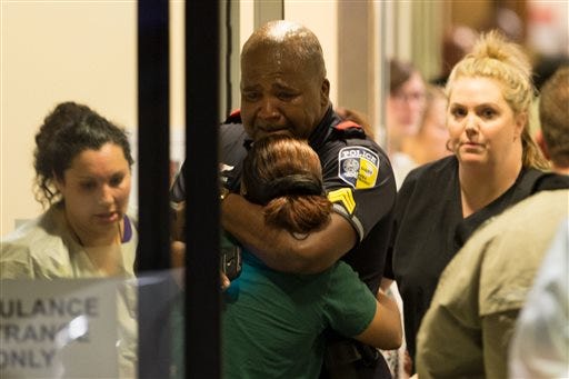 A Dallas Area Rapid Transit police officer receives comfort at the Baylor University Hospital emergency room entrance Thursday, July 7, 2016, in Dallas. Police say one rapid-transit officer has been killed and three injured when gunfire erupted during a protest in downtown Dallas over recent fatal shootings by police in Louisiana and Minnesota. (Ting Shen/The Dallas Morning News via AP)