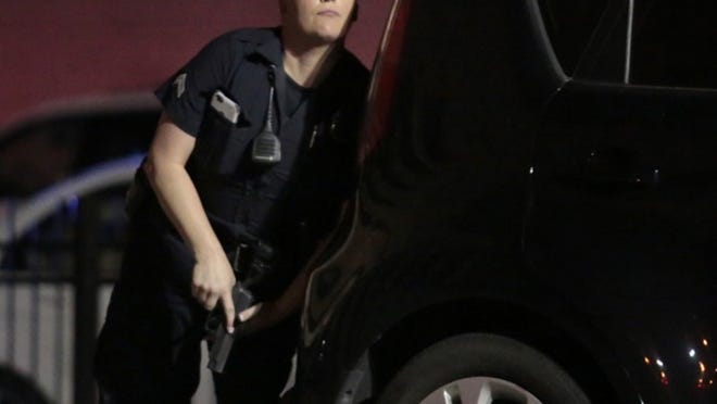 A police officer looks up while standing behind a vehicle, as police responded to shots being fired during a protest over recent fatal shootings by police in Louisiana and Minnesota, Thursday, July 7, 2016, in Dallas. Snipers opened fire on police officers during protests; several officers were killed, police said. (Maria R. Olivas/The Dallas Morning News via AP)