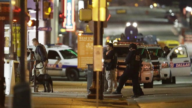 Law enforcement sweep the area after a shooting in downtown Dallas on Friday, July 8, 2016. At least two snipers opened fire on police officers during protests in Dallas on Thursday night; some of the officers were killed, police said. (AP Photo/LM Otero)