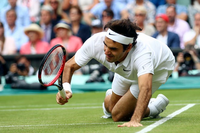 Roger Federer of Switzerland falls over during his men's semifinal singles match against Milos Raonic of Canada on day twelve of the Wimbledon Tennis Championships in London, Saturday, July 9, 2016.