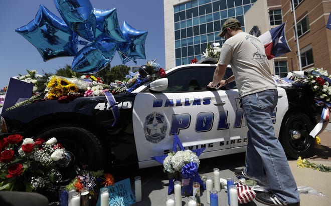 Michael O'Mahoney, a former police officer, places his patch on a make-shift memorial at the Dallas police headquarters Friday in Dallas. Five police officers were killed and several injured during a shooting in downtown Dallas Thursday night. THE ASSOCIATED PRESS