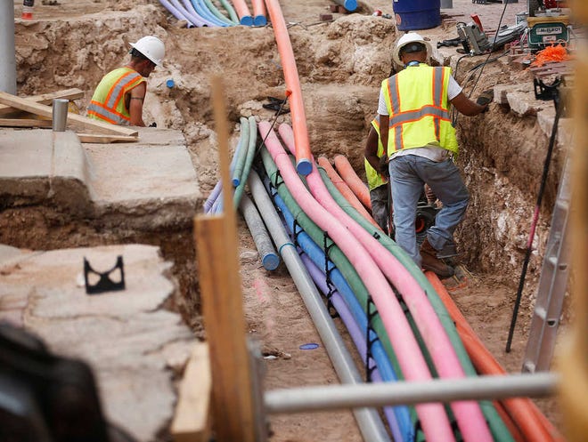 Construction workers bury color-coded utility lines along Avenue J near 13th Street on Wednesday in Lubbock.