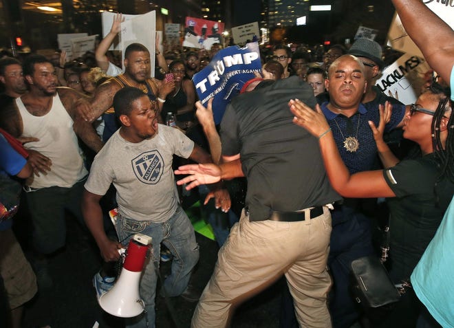 Rev. Jarrett Maupin, second from right, stands his ground as a Republican presidential candidate Donald Trump supporter, center, tries to interrupt marchers, as they take to the streets to protest against the recent fatal shootings of black men by police Friday, July 8, 2016, in Phoenix. (AP Photo/Ross D. Franklin)