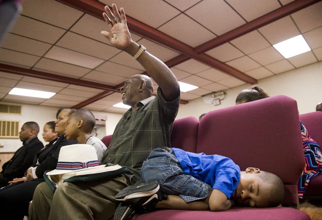Four-year-old Donovan Brown rests next to his grandfather Dwight Smith, 63, as they attend Sunday morning church services at Faith Temple Ministries Church of God in Christ along with Donovan's brother Orlando Brown, 9, during Sunday morning services on July 10 in Erie. ANDY COLWELL/