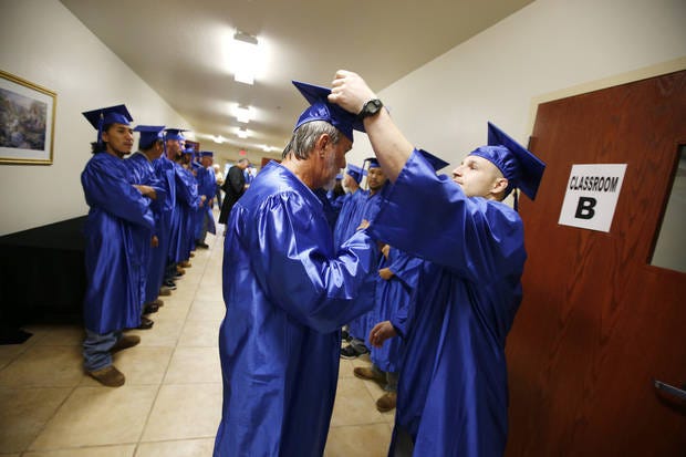 Tyler Carter assists Jerry Cox with his mortar board before the 2015 Tulsa Community College graduation ceremony at Dick Conner Correctional Center in Hominy. [Photo provided by Tulsa Community College]