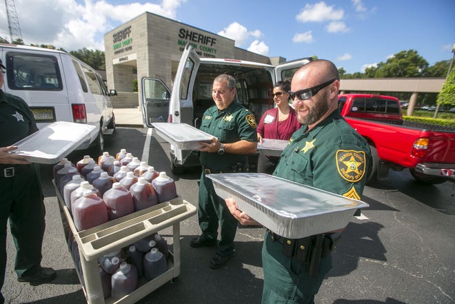 Marion County Sheriff's Office deputies unload the tea and brownies dropped off by Sonny's at MCSO Tuesday. (Alan Youngblood/Star-Banner)