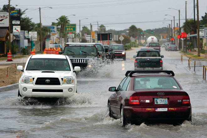 Looking east, cars drive through a flooded portion of Anastasia Boulevard at the foot of the Bridge of Lions after a recent storm.