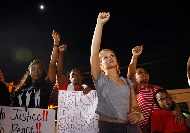 Ella Carr, center, puts her fist up during live music at a night rally in honor of Alton Sterling, outside the Triple S Food mart in Baton Rouge, Louisiana, on Monday. Sterling was shot and killed last Tuesday by Baton Rouge police.