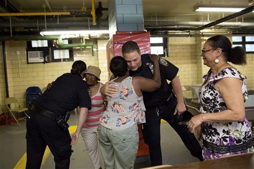 Police officer Mary Gillespie, left, of the 120th precinct on the Staten Island borough of New York, hugs Richmond Terrace Houses resident Gloria Phillips as fellow officer Jessi D'Ambrosio, center, hugs Barbara Shiel on Thursday, July 7, 2016. At right is Eunice Love president of the Richmond Terrace Houses. Love recalls years of seeing officers without knowing who they were. But D'Ambrosio and Gillespie? "They're such homeboy, homegirl," she says. "They know how to get along with people and relate and we love that." (AP Photo/Mary Altaffer)