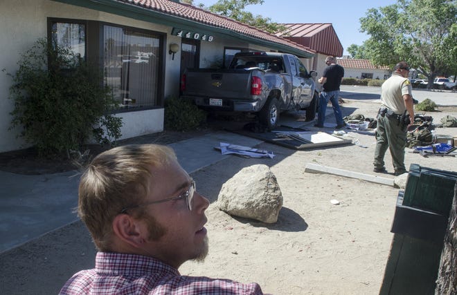 Staff of the High Desert Homeless Services look over the damage caused by a Sheriff's deputy which rolled against the building after a collision on Amargosa Road on Thursday. (James Quigg, Daily Press)