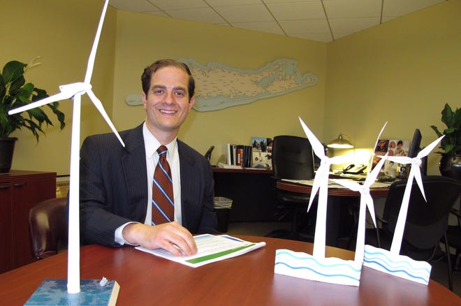 In this July 13, 2016 photo, Long Island Power Authority Chief Executive Officer Thomas Falcone sits in front of some models of offshore wind turbines at the utility's offices in Uniondale, N.Y. Falcone tells The Associated Press the utility is moving forward with plans to construct the nation's largest wind energy farm off eastern Long Island. (AP Photo/Frank Eltman)
