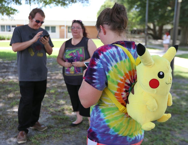 Victoria Baker, right, turns to check her phone as she plays "Pokemon Go" with her friends Trey Cosson, left, and Kayleigh Cosson as Gulf Coast State College hosted a "Pokemon Go" event Thursday, July 14, 2016, on the college campus in Panama City, Fla. (Patti Blake/News Herald via AP)