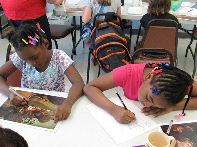 Mariya Curtis, 7, left of Lincoln and Aariyah English, 8, of Waukegan, work on their art they created Thursday at the Lincoln Public Library District. Curtis said she added a gnome and car and a fairy while English said she added a butterfly heart to her piece of work. Photo by Jean Ann Miller/The Courier