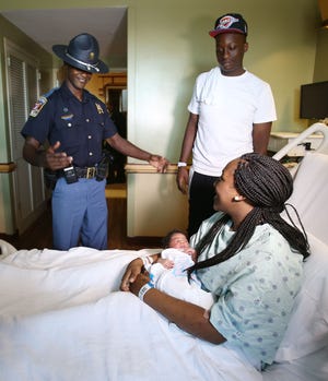 Alabama State Trooper Richard Pittman smiles as Jennifer Armstead holds her newborn baby girl, Kylie Taylor, as Armstead's boyfriend, Marcus Taylor, stands beside Pittman at the Women's Center at DCH Regional Medical Center in Tuscaloosa on Friday. Pittman delivered the couple's baby on Interstate 20/59 on Thursday. Pittman was assisting another officer at an accident when Taylor, who was stuck in traffic asked for help because Armstead was in labor.