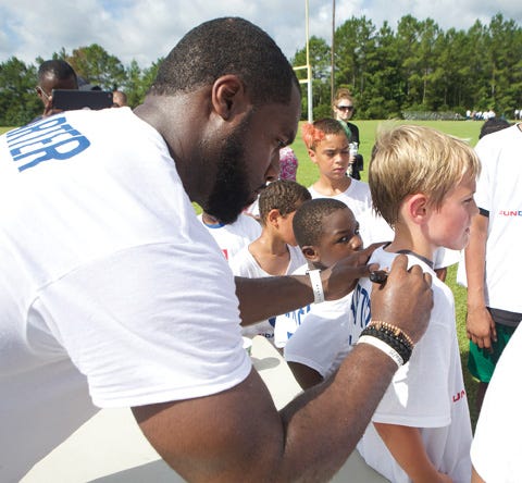 Havelock native Bruce Carter signs autographs at his youth football camp Saturday at the Havelock Recreation Center. Carter, now with the New York Jets, is approaching his sixth year in the NFL.