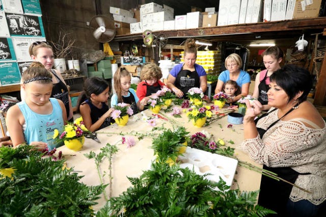 Expressions Flowers floral designer Kay Schlaefi, right, watches as members of the Van Buren and Cedarville Red Oak Service Unit of Girl Scouts help design some of the 750 Be Happy Bouquets on Friday, July 15, 2016, for delivery to local organizations and first responders duringr the Teleflora Make Someone Smile Week, Sunday through July 23. JAMIE MITCHELL/TIMES RECORD