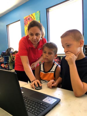 My School Tech Hub Teacher Rosita Jennings instructs YMCA summer camp students (from left) Breydan Sutton and Nick Williams how to code loops and algorithms associated with developing a mobile app game. Photo provided