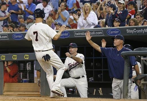 Minnesota Twins' Joe Mauer is greeted in the dugout after he scored against the Cleveland Indians during the seventh inning of a baseball game Saturday, July 16, 2016, in Minneapolis. Manager Paul Molitor is second from left. (AP Photo/Jim Mone)