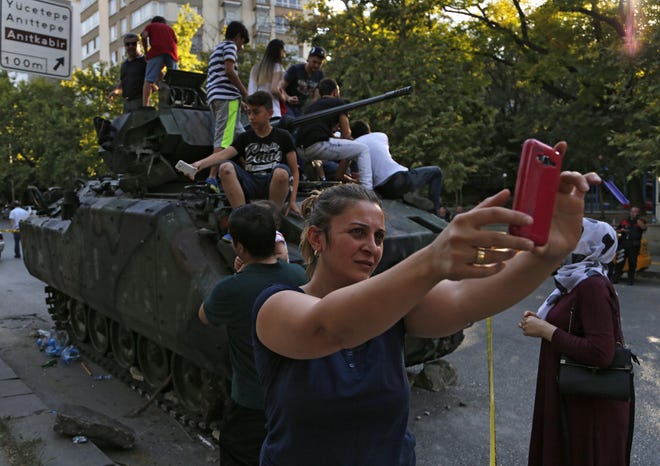 A woman takes a selfie in front a damaged Turkish military APC that was attacked by protesters near the Turkish military headquarters in Ankara, Turkey, Saturday, July 16, 2016. Forces loyal to Turkey's President Recep Tayyip Erdogan quashed a coup attempt in a night of explosions, air battles and gunfire that left dozens dead Saturday. Authorities arrested thousands of people as President Recep Tayyip Erdogan vowed those responsible "will pay a heavy price for their treason." (AP Photo/Hussein Malla)