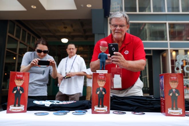 Howard Wilkinson, right, takes a picture of a bobblehead for sale of Republican presidential candidate Donald Trump, Sunday, July 17, 2016, in Cleveland. The Republican National Convention starts Monday, in Cleveland. (AP Photo/John Minchillo)