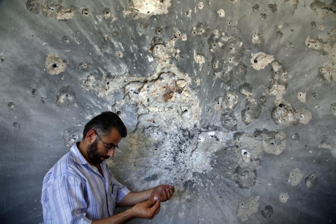 FILE - In this Aug. 5, 2012 file photo, a Syrian man holds bullets he picked from the wall of a damaged house in the town of Atareb, on the outskirts of Aleppo, Syria, Sunday, Aug. 5, 2012. Syrian opposition activists said Sunday, July 17, 2016 that government forces and their allies have closed the only road leading into and out of rebel-held parts of the northern city of Aleppo, besieging hundreds of thousands of people. The Britain-based Syrian Observatory for Human Rights says government forces and members of Lebanonâ?s Hezbollah group reached the Castello road Sunday, closing it and raising fears of a humanitarian crisis. (AP Photo/Khalil Hamra, File)