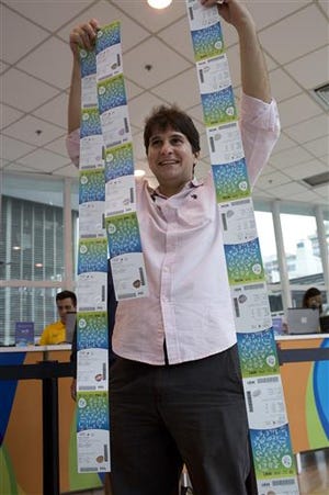 Wagner Ariano shows the Olympic tickets he bought at a shopping mall in Rio de Janeiro, Brazil, Monday, June 20, 2016. Two ticket offices opened Monday, providing tickets for the Rio 2016 Olympic and Paralympic Games. In the coming weeks, more than 30 offices will start operating in Rio as well as in the five cities where Olympic football matches will take place. (AP Photo/Silvia Izquierdo)