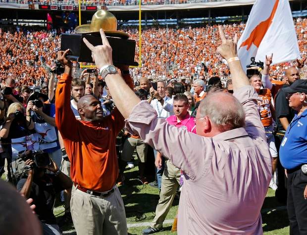 Texas coach Charlie Strong celebrates beating Oklahoma by lofting the Golden Hat Trophy last October. (Photo by Bryan Terry)