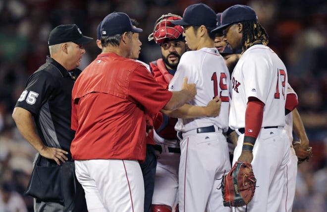 Koji Uehara is checked on by Red Sox manager John Farrell and teammates after suffering a right shoulder injury in the ninth inning of Tuesday's game.