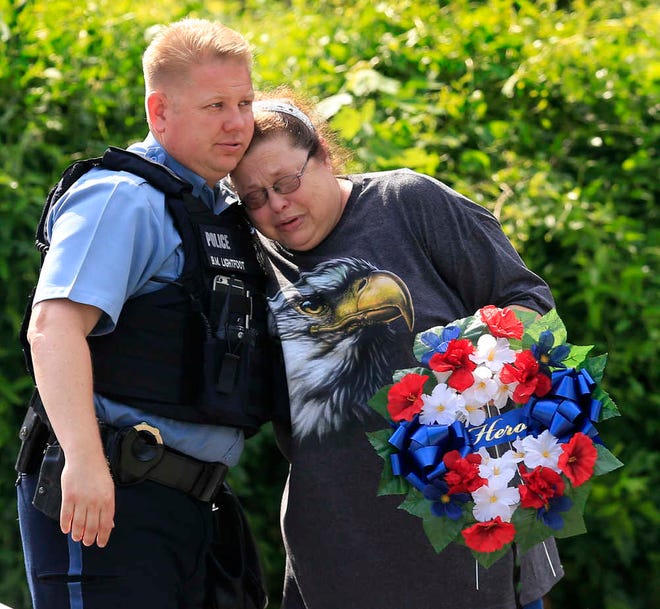Kansas City, Kan., police officer Brad Lightfoot, left, consuls Susan Goble at the shooting scene of a police officer in Kansas City, Kan., Tuesday, July 19, 2016. Goble knows the family of the fallen officer and hoped to place a wreath near the site of the shooting. A suspect in a drive-by shooting fatally shot Capt. Robert Melton, a 17-year veteran of the Kansas City, Kan., Police Department, on Tuesday as the officer was sitting in his patrol car, police said.