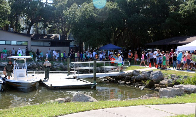 A line of children and their parents snakes along the walkway bordering the boat launch area of Bing's Landing at the start of a free Kids Fishing Clinic staged jopintly by the Flagler Sportfishing Club, the Florida Fish and Wildlife Conservation Commission and Fish Florida. NEWS-TRIBUNE PHOTOS/CAPT. MIKE VICKERS