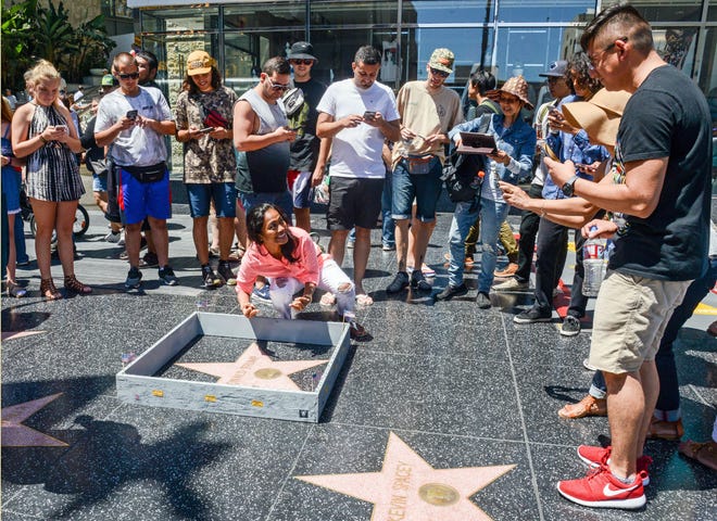 This Tuesday, July 19, 2016 photo provided by Nick Stern shows a six-inch high, concrete-appearing 'wall,' created by an artist known as Plastic Jesus, surrounding the Hollywood Walk of Fame star of Donald Trump in Los Angeles. It appeared Tuesday, the day the former reality TV star and entrepreneur secured the Republican nomination for president. Tourists snapped photos of the wall, topped with razor wire and plastered with "keep out" signs. The tiny wall was gone by Wednesday morning.
