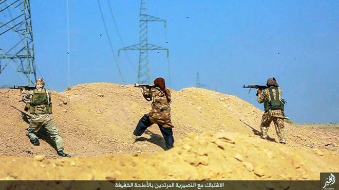 This undated picture released on June 28 by a militant website, which has been verified and is consistent with other AP reporting, shows fighters from the Islamic State group firing weapons toward Syrian troops and pro-government gunmen, in Deir el-Zour province, Syria. The Arabic caption on the photo reads, "Clashes with the renegade Nusariyah (racial slurs for Alawites) with light weapons."