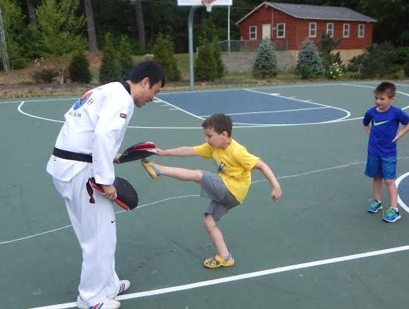 Aiden Creasi reaches up for a high kick during the Taekwondo program. Wicked Local Photo / Egan Davis