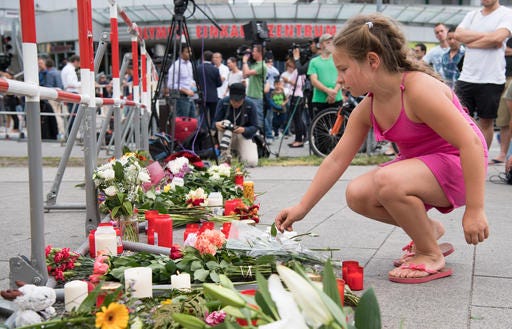 A girl puts down flowers in front of the Olympia shopping center were a shooting took place leaving nine people dead the day before on Saturday.