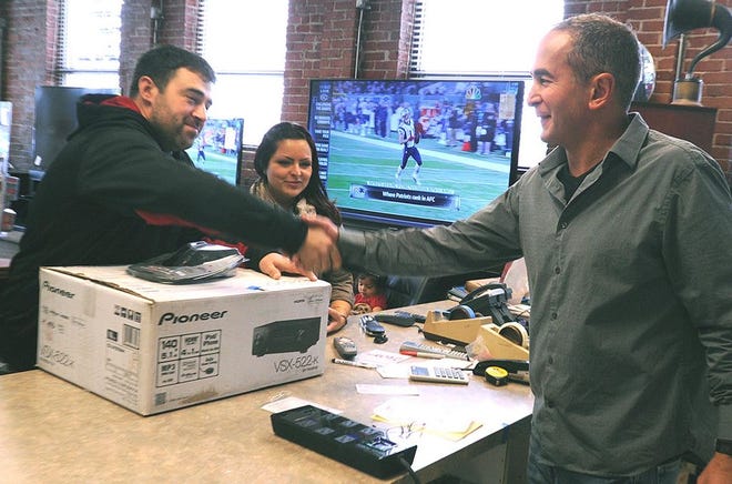 Bruno Afonso ( left ) reaches out to shake the hand of George Saber after he and his wife Melissa finalize the purhcase of a big screen TV and home theater setup in 2012.