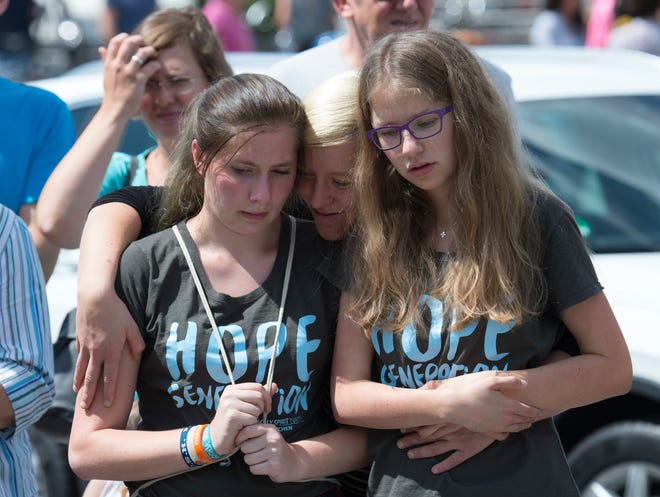 People mourn beside the Olympia shopping center where a shooting took place leaving nine people dead two days ago in Munich, Germany, Sunday, July 24, 2016.