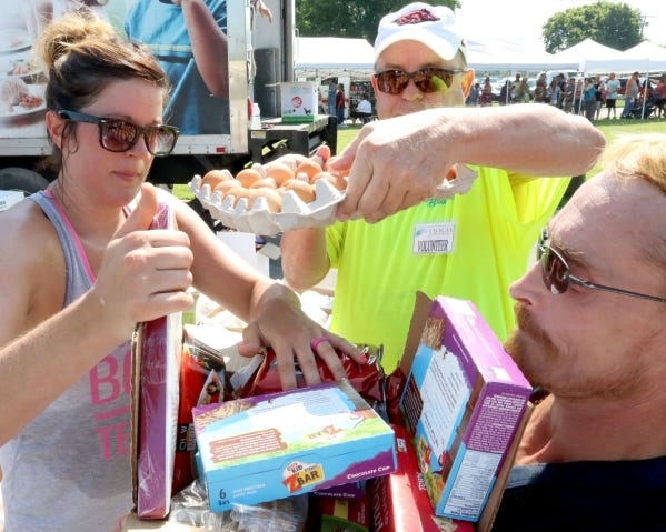 Volunteers Elizabeth Love, left, makes room for Stephen Adams to load eggs into a box of foodstuffs for Toby Gilmore on Saturday, July 23, 2016, during the Antioch in the Park food giveaway at Martin Luther King Jr. Park. JAMIE MITCHELL/TIMES RECORD