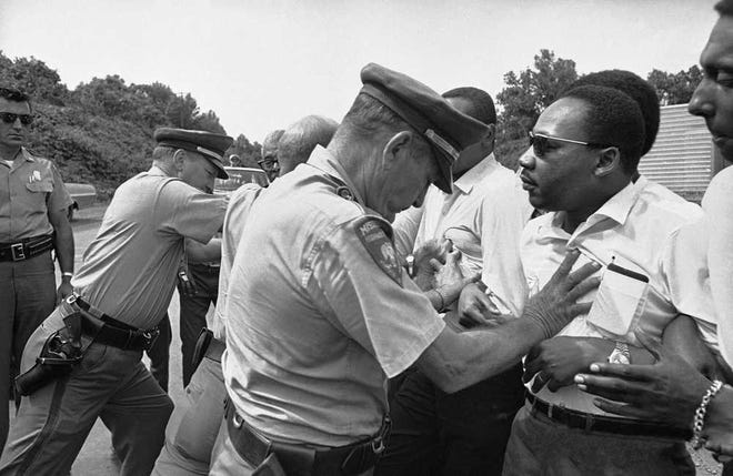 In this June 7, 1966, file photo, Mississippi Highway Patrolmen shove the Rev. Martin Luther King and members of his marching group off the traffic lane of Highway 51 south of Hernando, Mississippi.